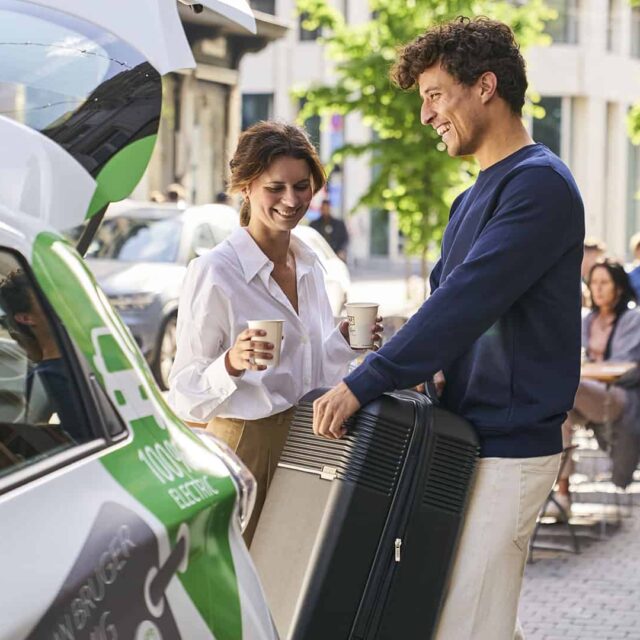 Mand og kvinde pakker kuffert i GreenMobility-bilen efter et besøg på loppemarked