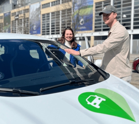 En kvinde og en mand der står ved en GreenMobility elbil foran Parken i København